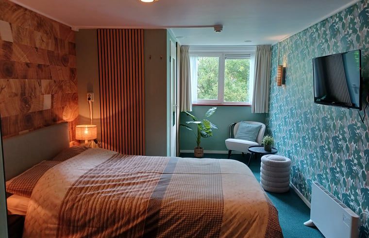 Stijlvolle slaapkamer met bloemenbehang in Huisje in Oosterend, Waddeneilanden.