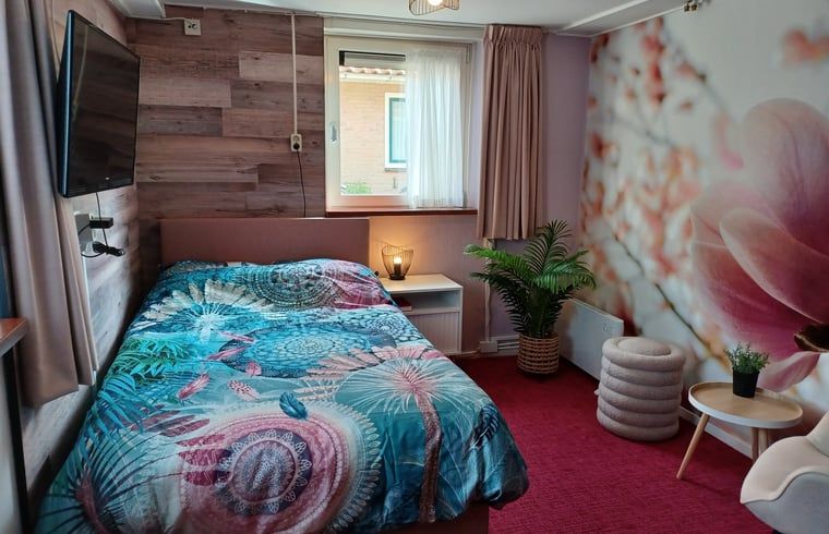Gezellige slaapkamer met kleurrijk dekbedovertrek in vakantiehuis Oosterend, Terschelling.