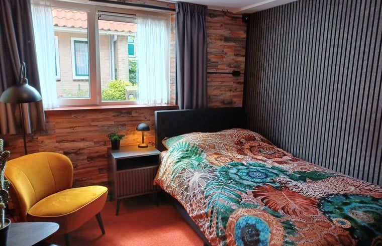 Knusse slaapkamer met houten accenten in vakantiehuis Oosterend, Waddeneilanden.