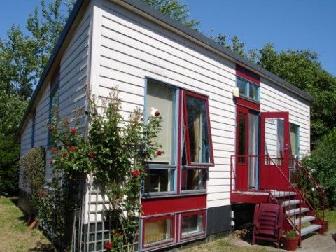 Glissando bungalow in Midsland Noord, Terschelling with charming wooden facade and red accents.