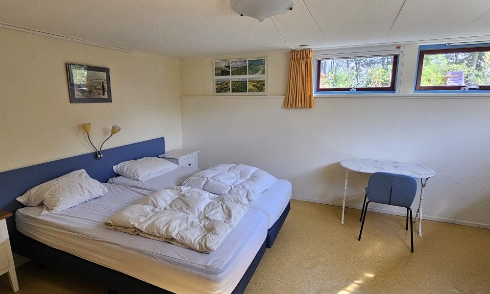 Bedroom in Glissando bungalow, Midsland Noord, Terschelling with work table and view of nature.