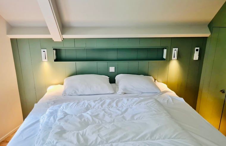 Comfortabele slaapkamer in vakantiehuisje in Ballum, Ameland met sfeervolle verlichting.