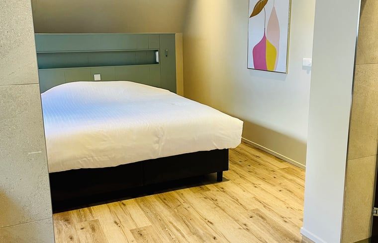 Stijlvolle slaapkamer met houten vloer in vakantiehuisje in Ballum, Ameland.