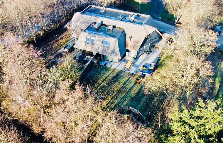Bovenaanzicht van vakantiehuisje in Ballum, Ameland omringd door bomen.