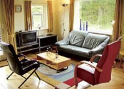 Gemtliches Wohnzimmer im Bungalow De Ouwe Pol, Buren, Ameland mit bequemer Sitzecke und Tageslicht.