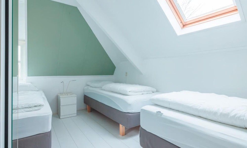 Lichte slaapkamer met eenpersoonsbedden in Noorderzon, Buren, Ameland met moderne inrichting.