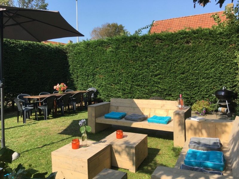 Zonnige tuin van Noorderzon vakantiehuis, Buren, Ameland met comfortabele zitplekken en veel groen.