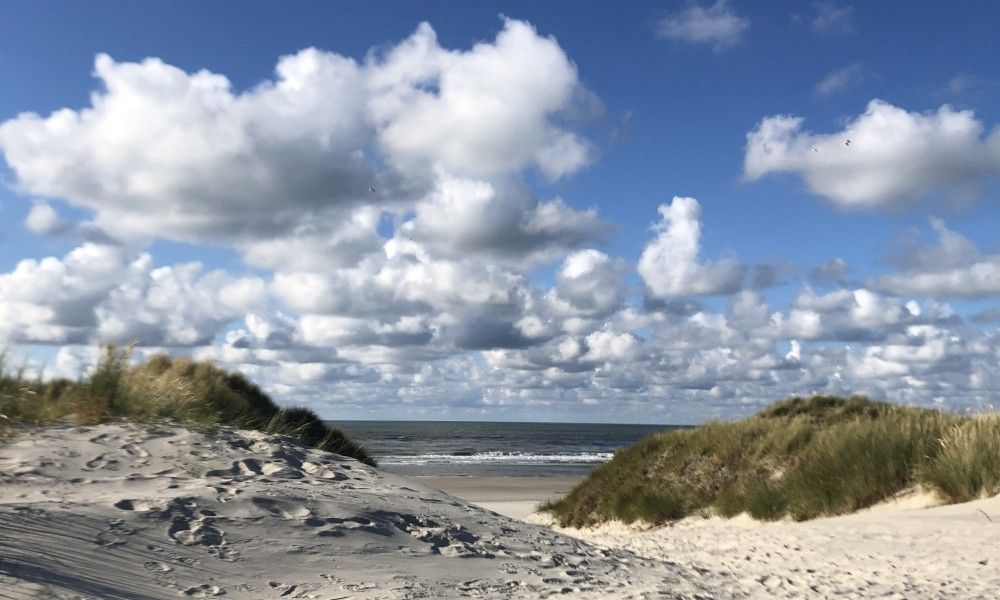 Prachtige strandduinen nabij Noorderzon, Buren, Ameland met uitzicht op de Noordzee en blauwe lucht.