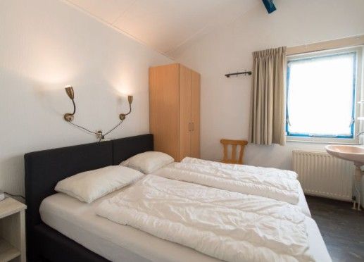 Bedroom in BORNRIF COTTAGE 6, Hollum, Ameland, with two single beds and natural light on the Wadden Islands.