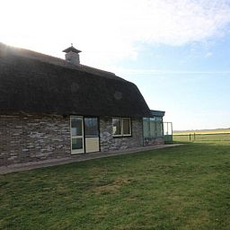 Rustieke buitenkant van de 6 pers. luxe villa met serre in De Cocksdorp, Texel, omgeven door natuur op de Waddeneilanden.