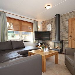 Gezellige woonkamer in de 6 pers. luxe villa met serre, De Cocksdorp, Texel, met open haard voor een knusse vakantie.