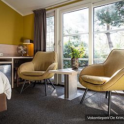 Gemuetliche Sitzecke im luxurioesen 2-Personen-Hotelchalet auf Texel, mit Blick auf die gruene Umgebung von De Cocksdorp.