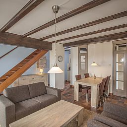 Dining area and stairs in Type T-3 vacation home, De Cocksdorp, Texel, with wooden elements.