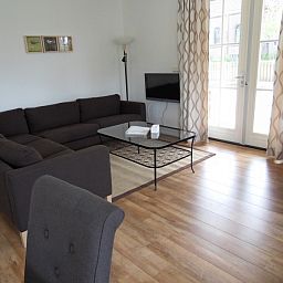 Gemuetliches Wohnzimmer des Ferienhauses Typ 7 - 2107 in De Cocksdorp Texel mit grosser Sitzecke und Tageslicht.