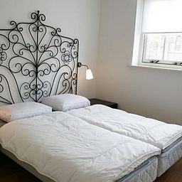 Schlafzimmer in Typ 7 - 2107 Ferienhaus De Cocksdorp Texel mit elegantem schmiedeeisernem Kopfteil und zwei Betten.