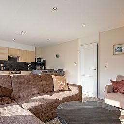 Offener Wohnbereich im Ferienhaus Slufterhoek 102, De Cocksdorp, Texel mit einer gemuetlichen Sitzecke und Blick auf die Kueche.