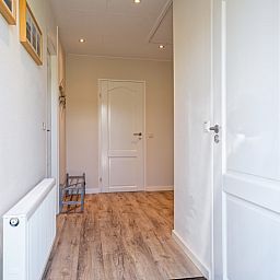 Heller Flur im Ferienhaus Slufterhoek 102, De Cocksdorp, Texel mit Holzboden und Zugang zu mehreren Raeumen.