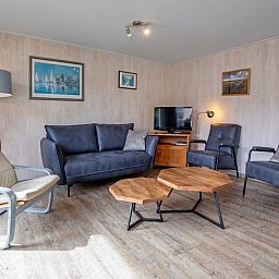 Bungalow Tamarisk 206 in De Cocksdorp, Texel, bietet ein gemuetliches Wohnzimmer mit TV und Sitzgelegenheit.