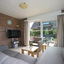 Gezellige woonkamer in Bungalow De Witte Hoek 6 Pers., De Cocksdorp, Texel met comfortabel interieur en tuinzicht.