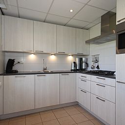 Moderne keuken in Bungalow De Witte Hoek 6 Pers., De Cocksdorp, Texel met strakke witte kastjes en inbouwapparatuur.