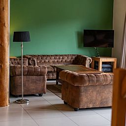 Gezellige zithoek in Huisje in De Cocksdorp, Texel, met groene muur en moderne voorzieningen.