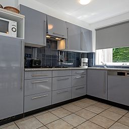 Moderne Kueche des Ferienhauses Slufterduin 098 in De Cocksdorp, Texel, mit grauen Schraenken und komplett ausgestattet.