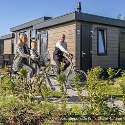 Die Familie radelt am Chalet Typ Vuurtoren de Luxe in De Cocksdorp auf Texel vorbei, umgeben von Natur.