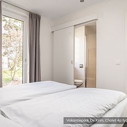 Schlafzimmer im Chalet Typ Texel de Luxe, De Cocksdorp, Texel mit bequemen Betten und Gartenblick.