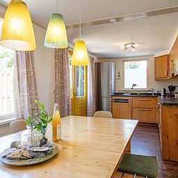 Stilvolle Essecke im Ferienhaus Ganzenvlucht, De Cocksdorp, Texel, mit Blick auf den Garten und die moderne Kueche.