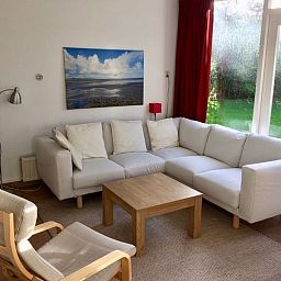 Gemuetliche Sitzecke im Bungalowpark Slufteroord, De Cocksdorp Texel, mit bequemem Sofa und Blick auf den gruenen Garten.