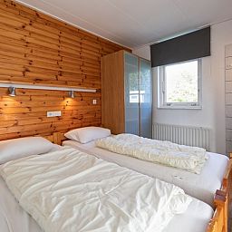 Bedroom with wooden accents in Bungalow Tamarisk 190, De Cocksdorp, Texel.