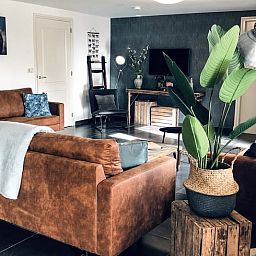 Stilvolles Wohnzimmer im Ferienhaus in De Cocksdorp, Texel, mit bequemen Ledersofas.