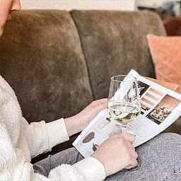 Entspannter Moment im Ferienhaus in De Cocksdorp, Texel, mit einem Glas Wein und einer Zeitschrift auf dem Sofa auf den Watteninseln.
