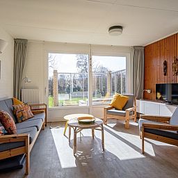 Helles Wohnzimmer im Ferienhaus Slufteroord 292 mit Blick auf den Garten in De Cocksdorp, Texel.