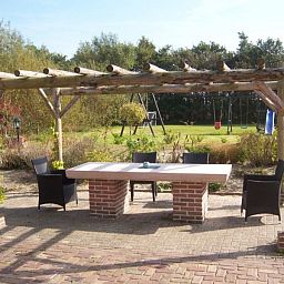 Gemuetliche Terrasse bei Paal 86 Texel in De Cocksdorp mit Pergola und Gartenblick.