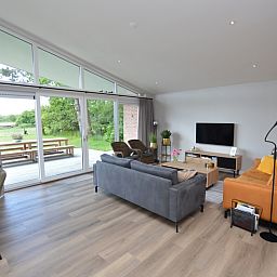 Bright living room of Orchismient 49 vacation home in De Koog, Texel with views of greenery and spacious seating area.