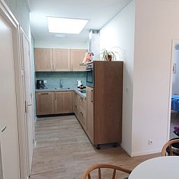 Modern kitchen in vacation home Huisje Quirijn, De Koog Texel with wooden cabinets and light through skylight.