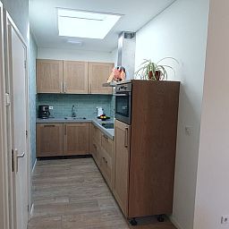 Compact kitchen in Cottage Quirijn, De Koog Texel with sleek wooden finish and modern appliances.