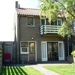 Backyard of The Duinputter vacation home in De Koog Texel with balcony and green view.