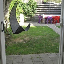 Cozy garden of The Duinputter in De Koog Texel with rocking chair and colorful chairs.