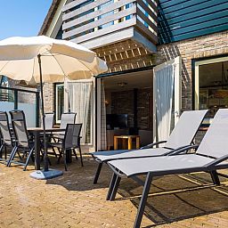 Sunny terrace at Villa, De Koog, Texel with deck chairs and parasol for relaxing moments.