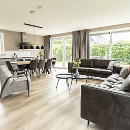 Stylish living room of Villa 17 in De Koog, Texel with open kitchen and garden view for a comfortable stay.