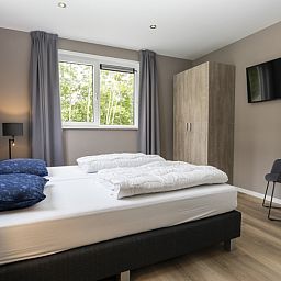 Bedroom in Villa 17, De Koog, Texel with comfortable double bed and view of green nature for ultimate relaxation.