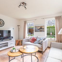 Modern living room of vacation home Honeysuckle 81 in De Koog, Texel with flat-screen TV and cozy furnishings for a relaxing stay.