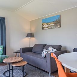 Cozy living room in Chalet Bregkoog 227, Chaletpark Bregkoog, De Koog, Texel with comfortable sofa and colorful armchair.