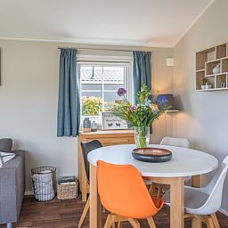 Dining area Chalet Bregkoog 227, Chaletpark Bregkoog, De Koog, Texel with modern chairs and decorative flowers.