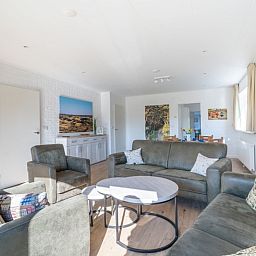 Bright living room of Orchismient 14 vacation home De Koog Texel with comfortable sofas and access to dining area.