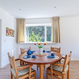 Dining area in Orchismient 14 vacation home De Koog Texel with round table and garden view.