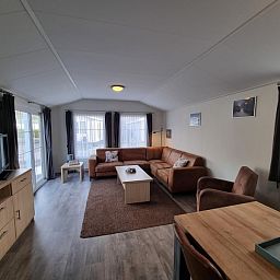 Spacious living space in Chaletpark Bregkoog - Chalet Bregkoog 235, De Koog, Texel with lots of natural light and access to terrace.