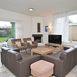 Cozy living room of vacation home Epelaan 31 in De Koog, Texel with modern furnishings and garden views.